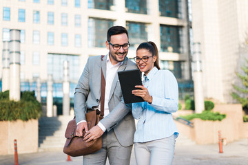 Team of two young successful happy confident attractive business people, looking at tablet for business plans and designer projects.