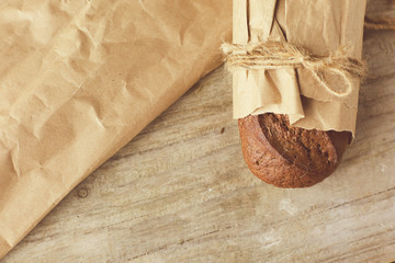 A loaf of Bread packed in paper on wooden table.