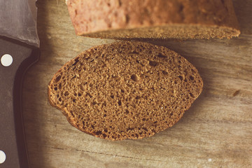 Sliced loaf of Bread and knife on wooden table. Cropped photo.
