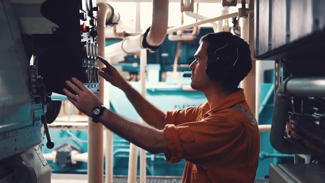 Marine engineer inspecting ship's engine in engine control room ECR. Seamen's work.