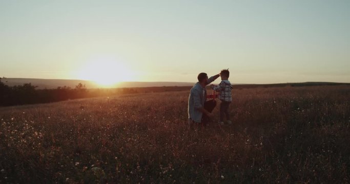 A cute boy with his dad making bubbles in the middle of field, spending good time. Shot on Red Epic