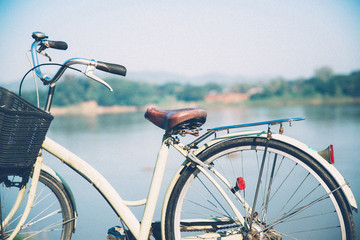 Fototapeta na wymiar Bicycle near lake during sunset.Vintage bike near the lake in the evening, warm sunset view.