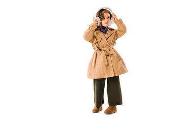beautiful little child in trench coat with headphones isolated on white
