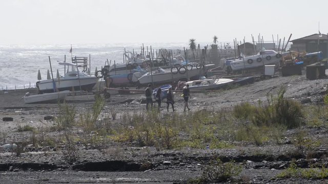 passaggio attraverso la spiaggia con ricovero di natanti e sullo sfondo il mare con forte vento