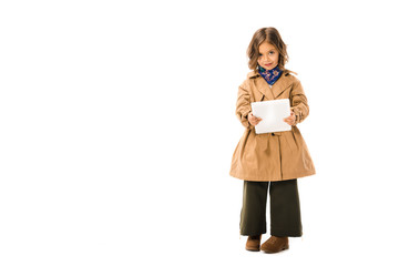 beautiful little child in trench coat using tablet and looking at camera isolated on white