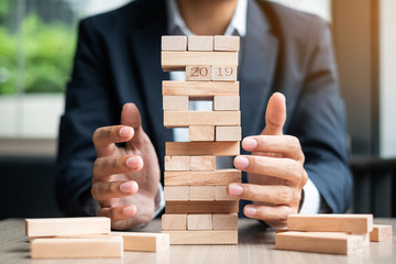 Businessman hand placing or pulling wooden block on the tower. 2019 Business planning, Risk Management, Solution and strategy Concepts