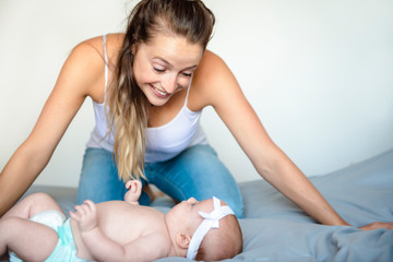 Obraz premium Portrait of a beautiful mother with her 2 month old baby in the bedroom
