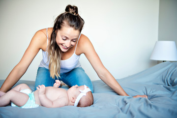 Obraz premium Portrait of a beautiful mother with her 2 month old baby in the bedroom