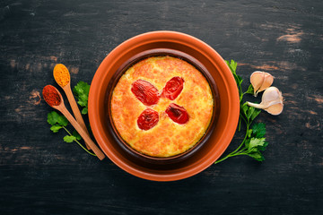Baked cheese with tomatoes in a plate. Georgian cuisine. On the old wooden background. Free space for text. Top view.