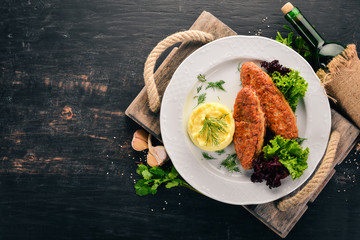 Cutlets of meat with mashed potatoes on a plate. On the old wooden background. Free space for text....