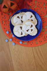 Fototapeta na wymiar Halloween cookies filled with chocolate in shape of a skull on a plate on wooden table 
