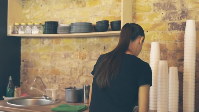 Smiling waitress giving cup of coffee to the customer, he doing paypass payment.