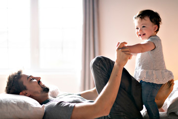 Fototapeta premium Young father with child girl on bed at home