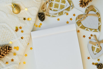 Cozy magical Christmas background for writing on a blank sheet of notebook on white with cones, sweater, stars and decor. Top view.