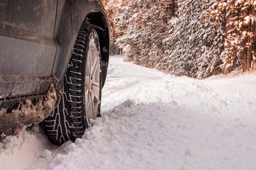 Car tires on winter road covered with snow. Vehicle on snowy alley in the morning at snowfall