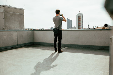rear view of young man photographing a city skyline with his smartphone