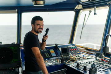 Marine navigational officer is reporting by VHF radio during navigation watch. Bridge GMDSS watch
