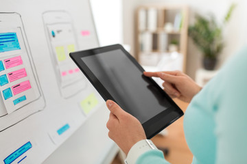 technology, user interface design and people concept - hands of ui designer or developer with tablet pc computer and smartphone sketches on flip chart at office