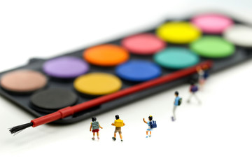 Miniature people : Children students with watercolor paints and paintbrushes for painting.