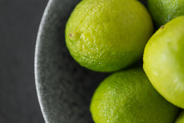 food, healthy eating and vegetarian concept - close up of whole limes in bowl