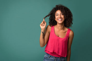African-american woman touching her curly hair on turquoise background