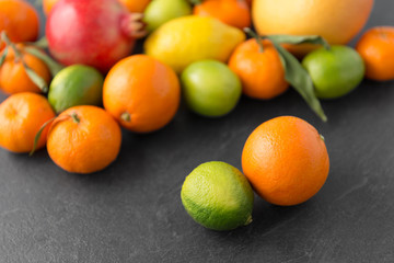 food, healthy eating and vegetarian concept - close up of citrus fruits on stone table