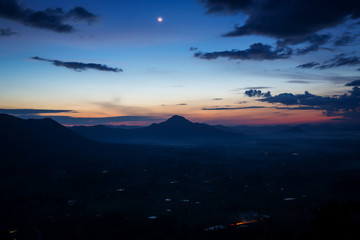 Cold morning mountain range in the fog, view on countryside landscape, blue winter with dawn dark sky.