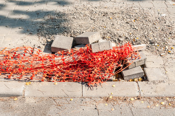 Orange plastic safety net or barrier on the street to protect people for step in to the damaged...