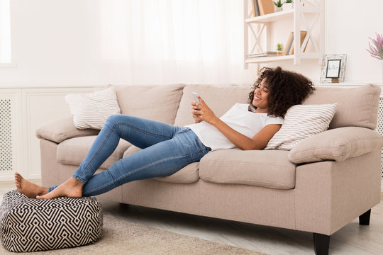 Happy African-american Girl Messaging On Smartphone At Home