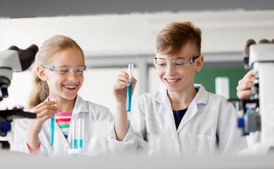 education, science and children concept - kids with test tubes studying chemistry at school laboratory