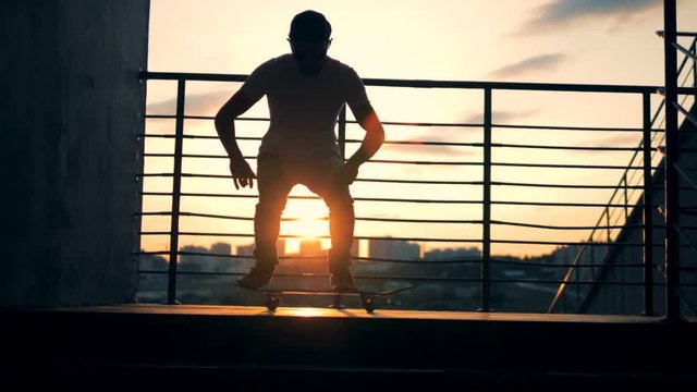 A skater doing stunts on a sunset background, slow motion.