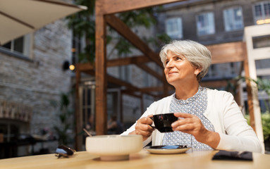 old age, leisure, retirement and people concept - happy senior woman drinking coffee at street cafe