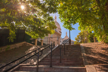 Typical sunny Montmartre staircase to Sacre-Coeur in the morning and sunlight coming through the trees, quarter Montmartre in Paris, France