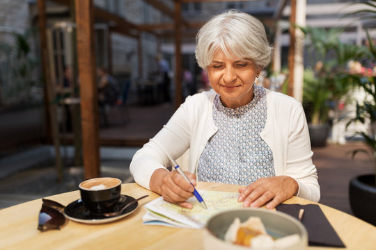 Travel, Tourism, Retirement And People Concept - Happy Senior Woman With Map And Coffee At Street Cafe