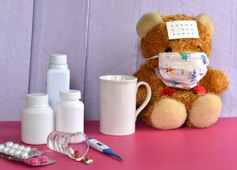 Medicine and teddy bear with mask on the pink table ,Sick concept