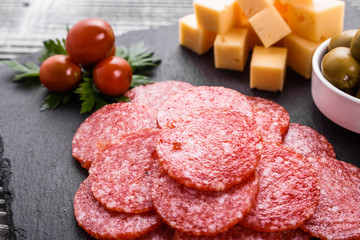 delicious sliced salami on a stone plate wooden background