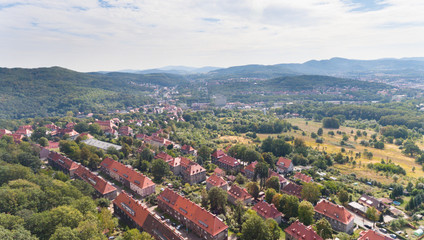 Old European town with red roof buildings and green hills drone view from above