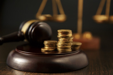 Close-up Of A Person Hand Stacking Coins In Front Of Mallet Over Gray Background