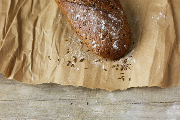 A loaf of Bread packed in paper on wooden table.