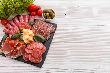 Cold smoked meat plate on a rustic wooden background