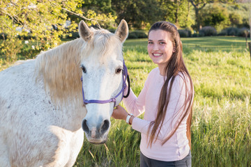 Teenage girl with a white Boerperd horse holding his head collar looking at the camera smiling.