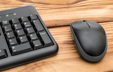 Computer keyboard with computer mouse on wooden table.