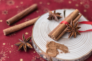 Cinnamon sticks, cinnamon powder, star anise on wood. Red background
