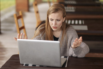 Frustrated worried woman looks at laptop shocked by bad news .