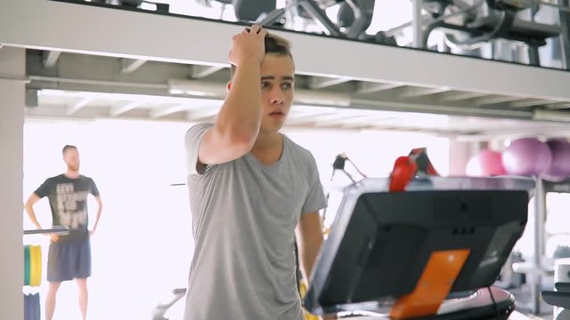 Young beginner man running on treadmill in gym