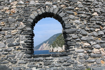 Mura in pietra con finestra ad arco sul mare