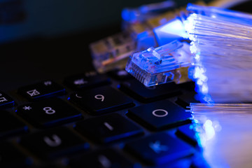 Internet switches on laptop computer keyboard, glowing optical fibres close up shot background...