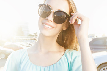 Beautiful young girl with sunglasses smiling on sunny street