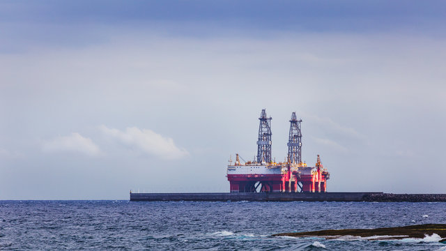 Two masts of oil rig on sea near coastline.