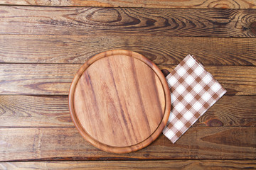 Brown old vintage wooden table with framed checkered tablecloth and pizza cutting board.Thanksgiving day and Cristmas table concept. Top view and copy space. Selective focus